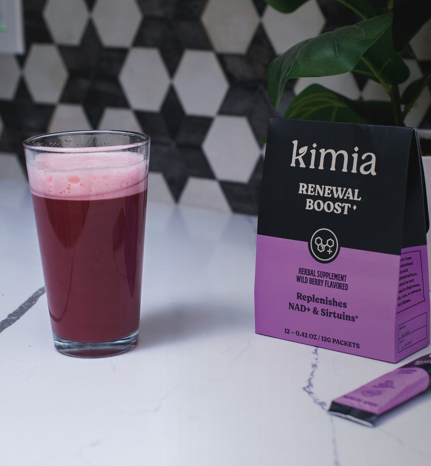 A glass of the wild-berry renewal blend on a kitchen counter beside the carton